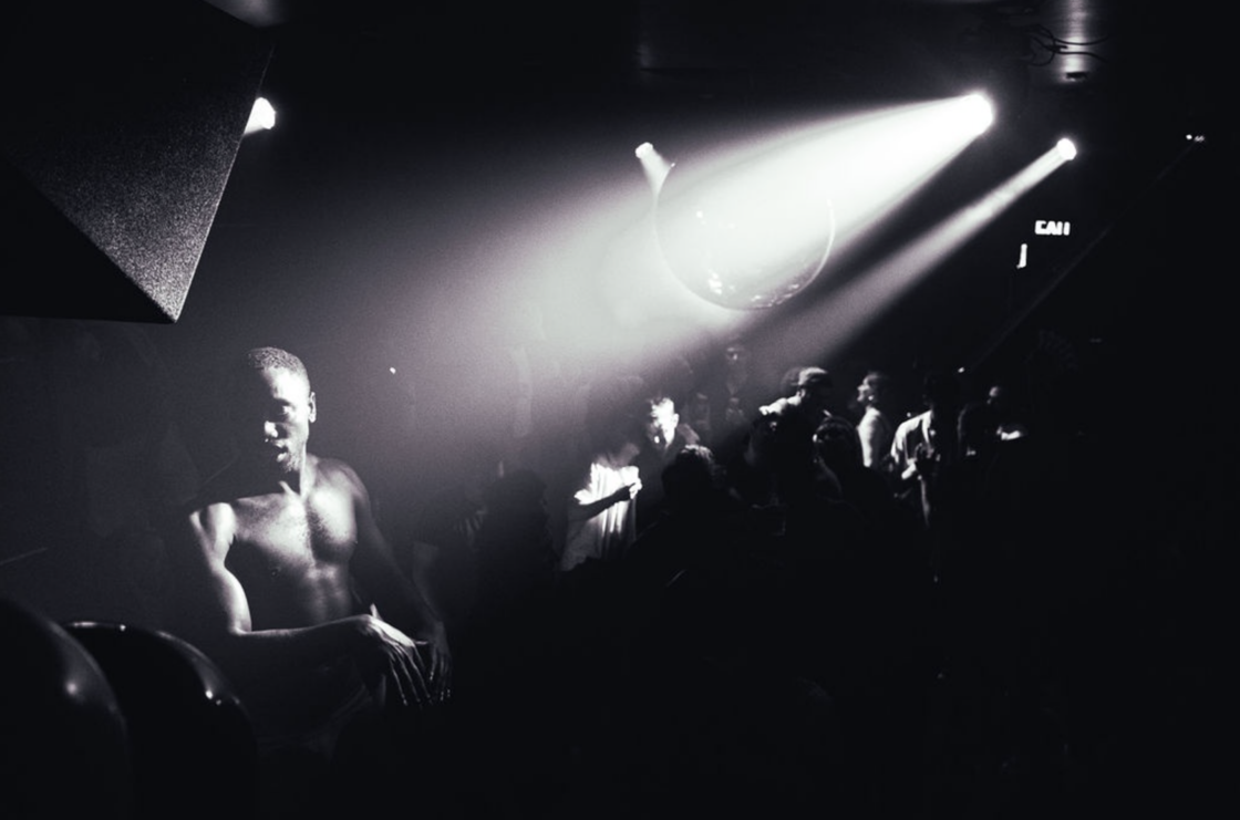 A shirtless dancer moves under a disco ball at The Ritz Bar & Lounge.