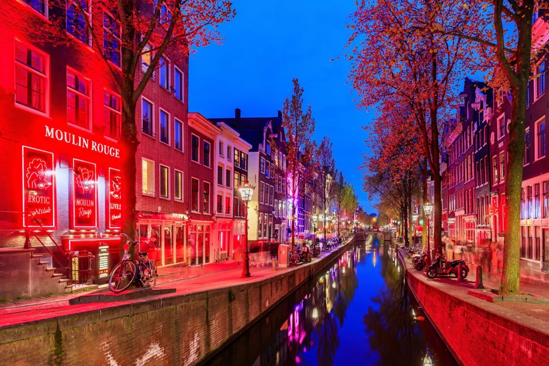Amsterdam's Red Light District, lit up in red light, pictured at night looking down the canal.