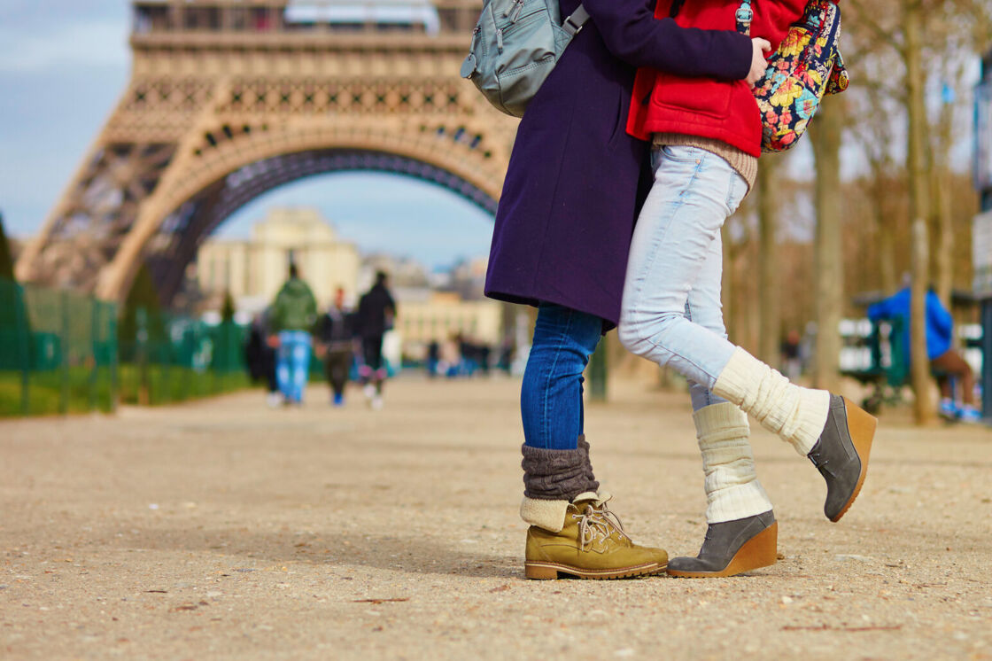 A same-sex couple kisses in front of the Eiffel Tower.