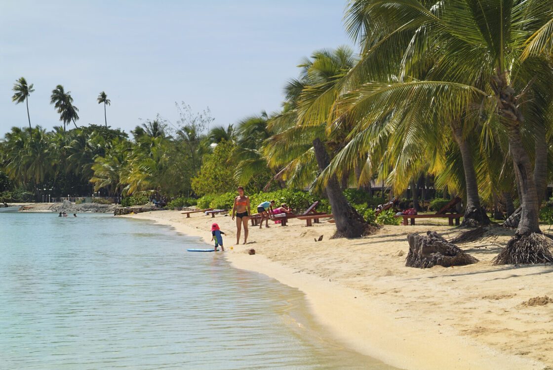 Malolo Laila Island in Fiji pictured at daytime, with unidentified beachgoers playing in the water.