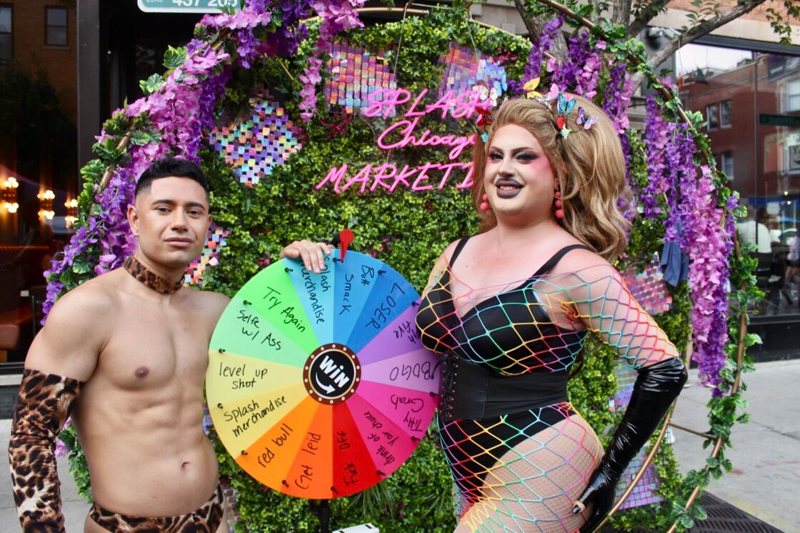 A shirtless man and drag queen pose with a wheel outside of Splash at Chicago's Market Days.