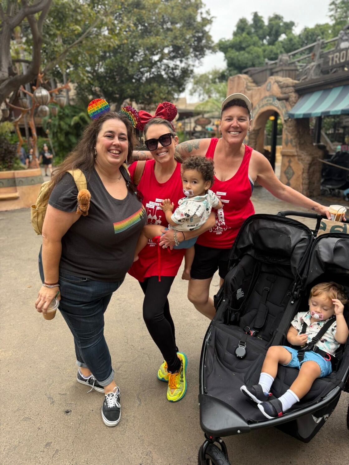 Three women smile with two kids in strollers at Anaheim Gay Days in Disneyland.