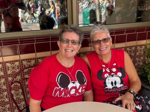 Two women smile while eating outdoors at Disneyland during Anaheim Gay Days.