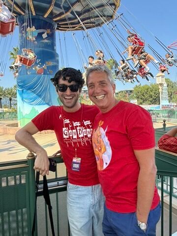 Two men smile in front of the swings at California Adventure during Anaheim Gay Days.