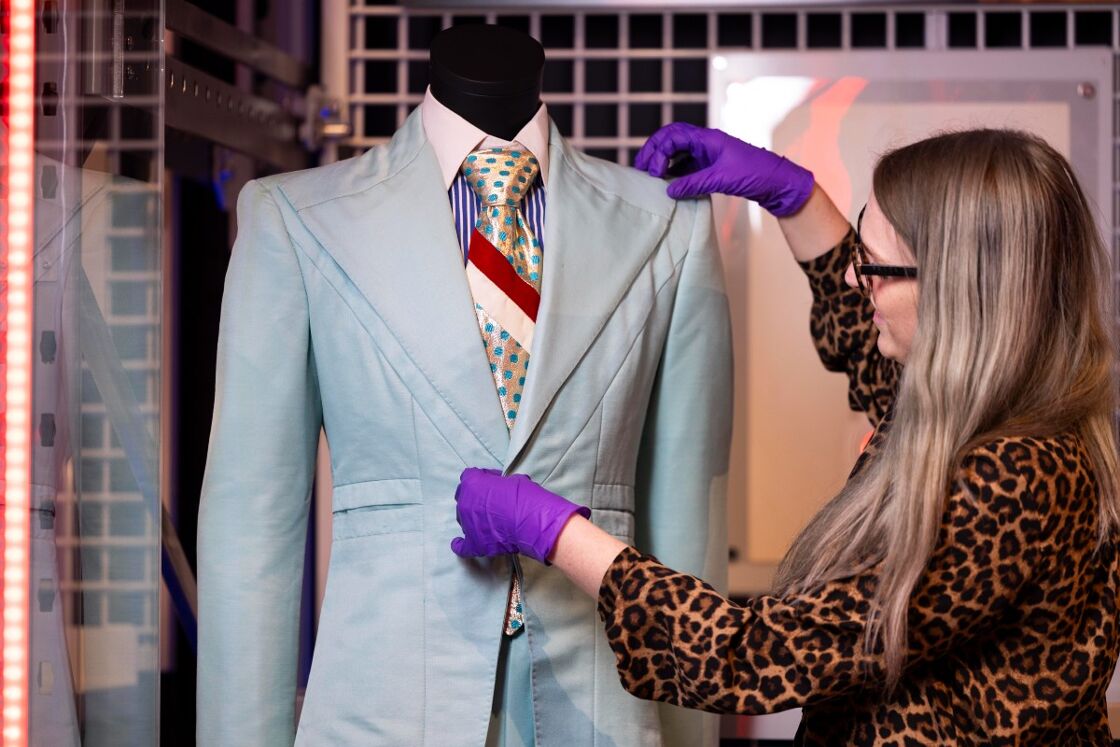 A V&A Conservator adjusts a suit designed by
Freddie Burretti for David Bowie in the 1972
'Life on Mars?' music video during installation
of the David Bowie Centre at V&A East
Storehouse. 