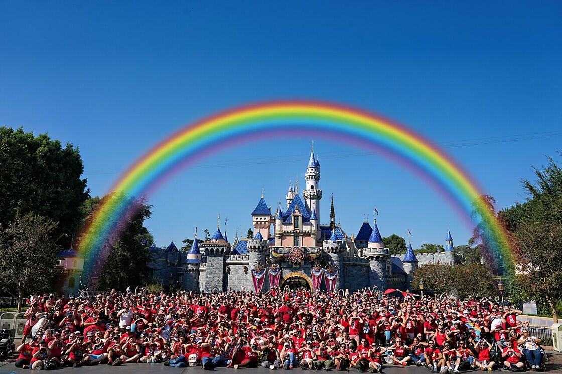 Attendees of Anaheim Gay Days pose in front of Cinderella's Castle at Disneyland in red t-shirts.