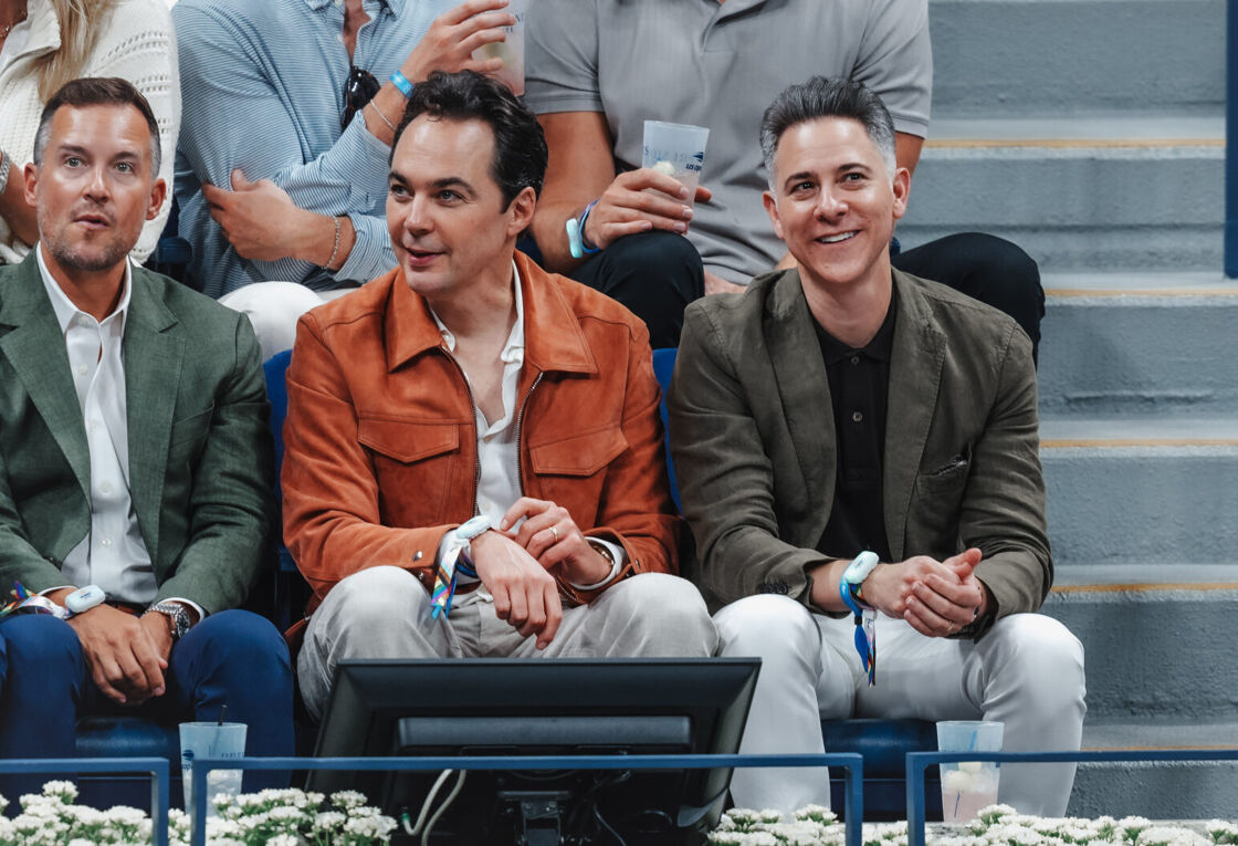 Jim Parsons watches the US Open from the audience in an orange jacket.