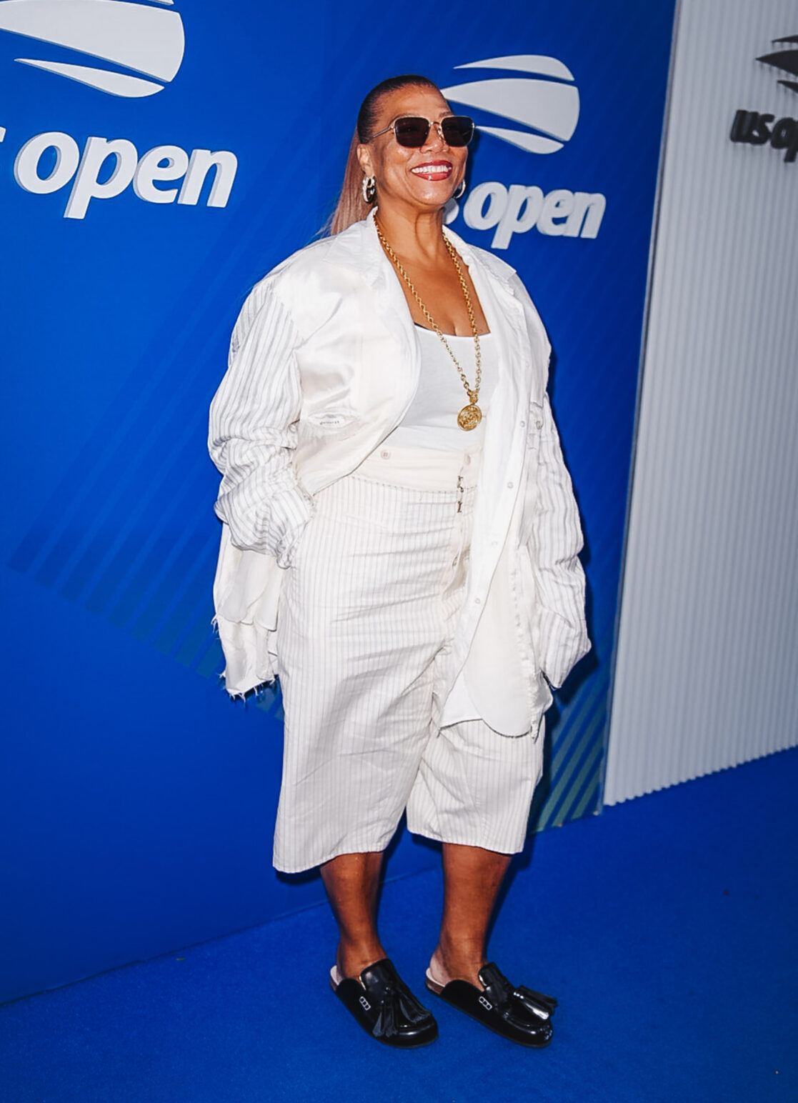 Queen Latifah smiles wearing an all white outfit at the US Open.