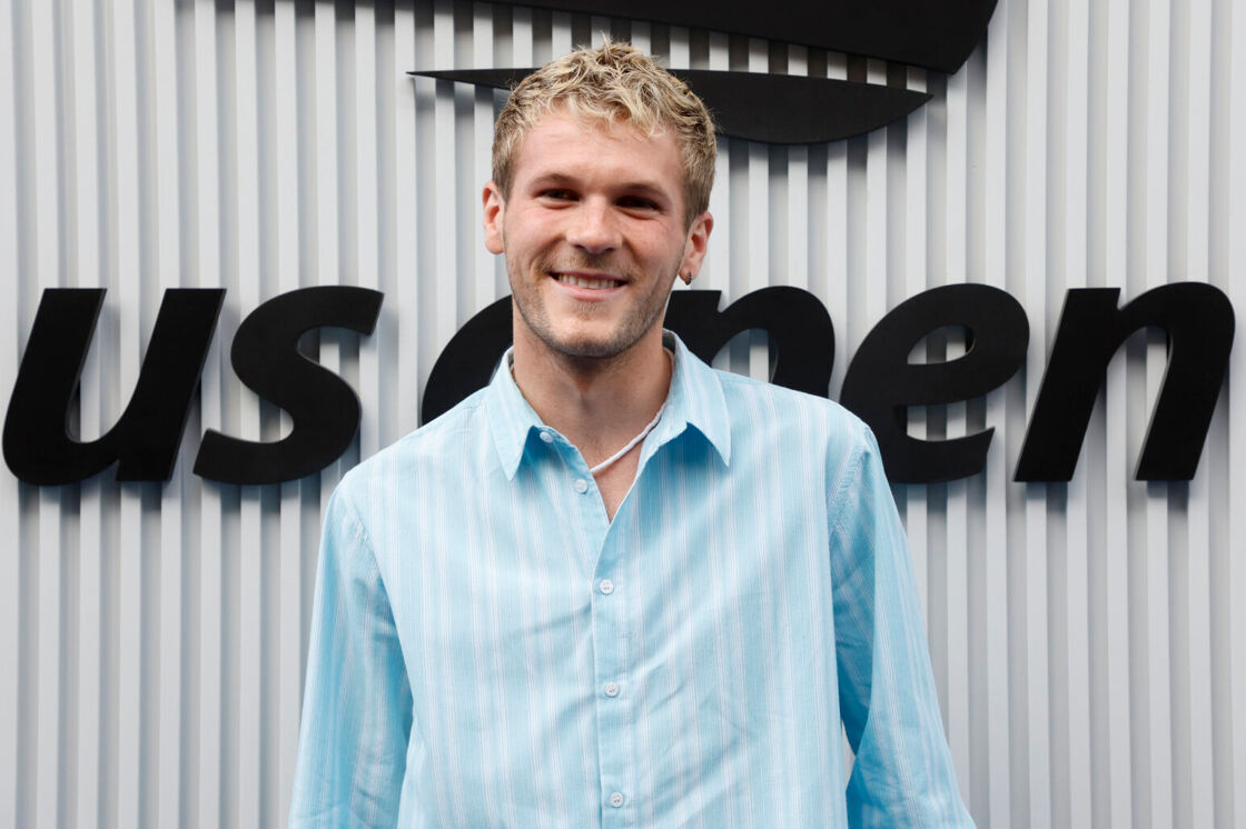 Davis Burleson smiles in a light blue long sleeved shirt at the US Open.