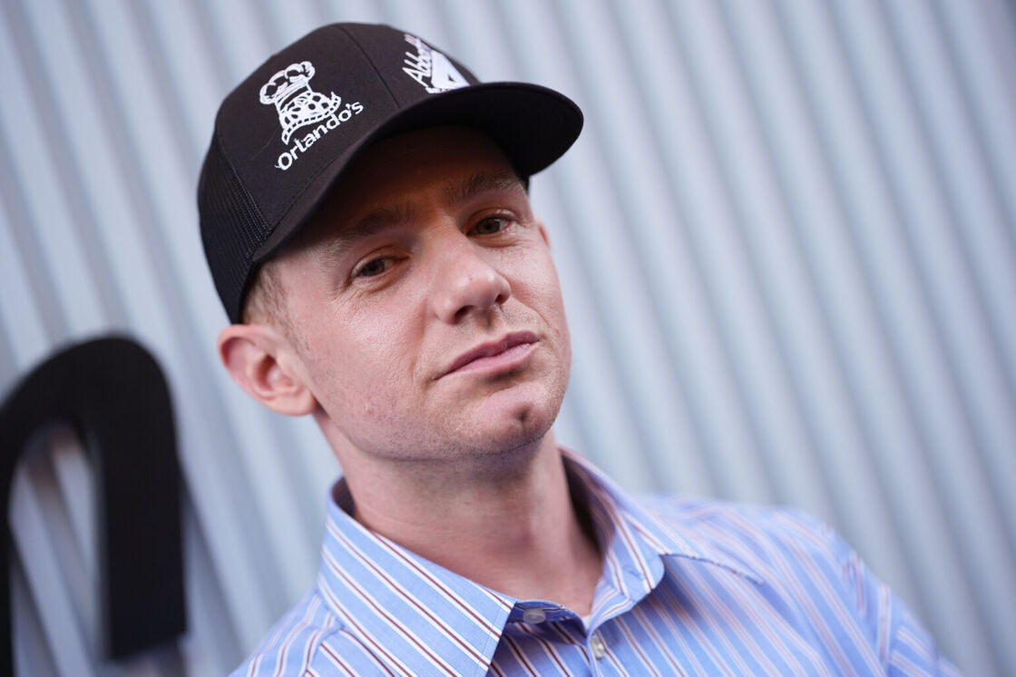 Chris Perfetti smiles softly in a black baseball hat at the US Open.