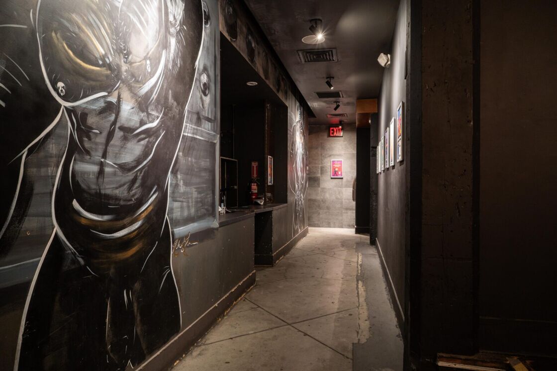 The entrances to the bathrooms and coat check at G Lounge, decorated with an illustrated caricature of a muscled-up man.