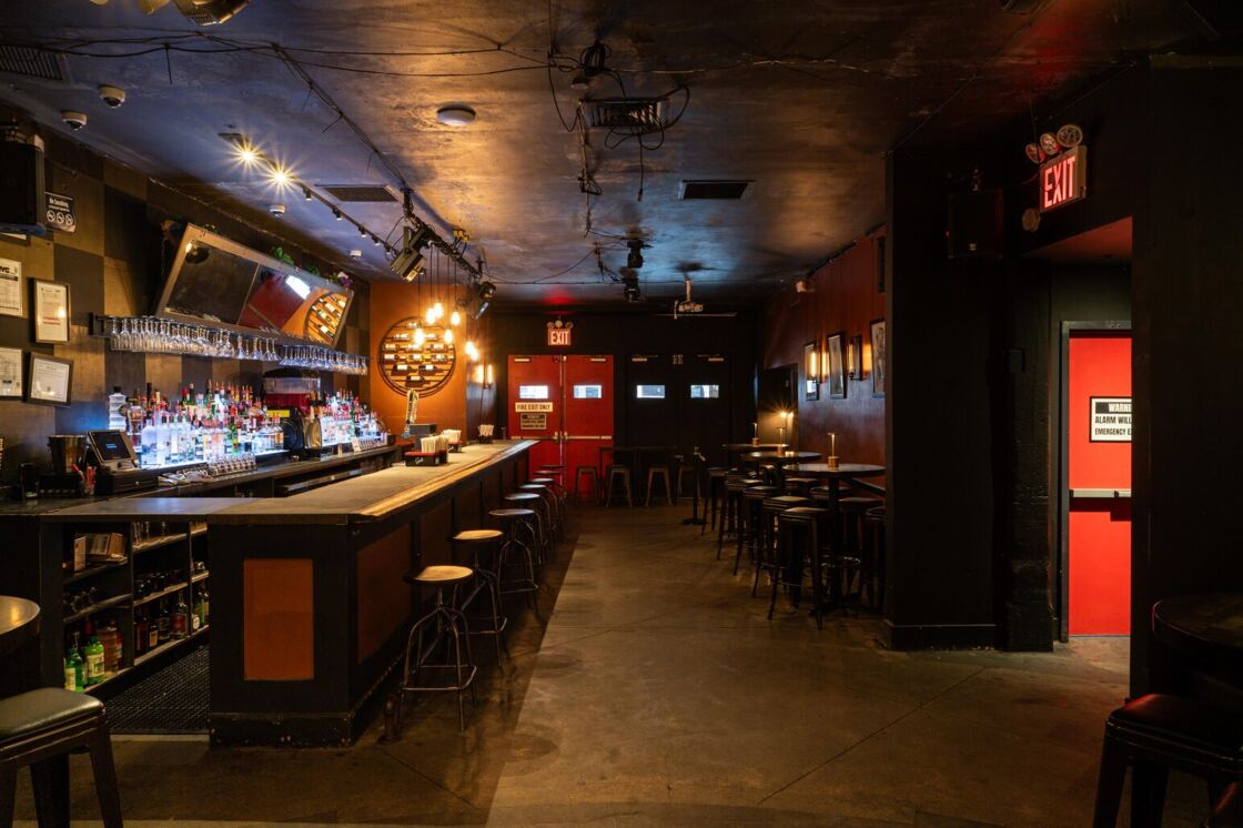 G Lounge pictured from the middle of the dance floor, showing a bar, seating, and exit doors in the middle and on the right.