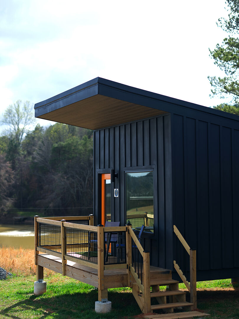 A custom-built black cabin is pictured near a lake at Blue Moon Campgrounds.