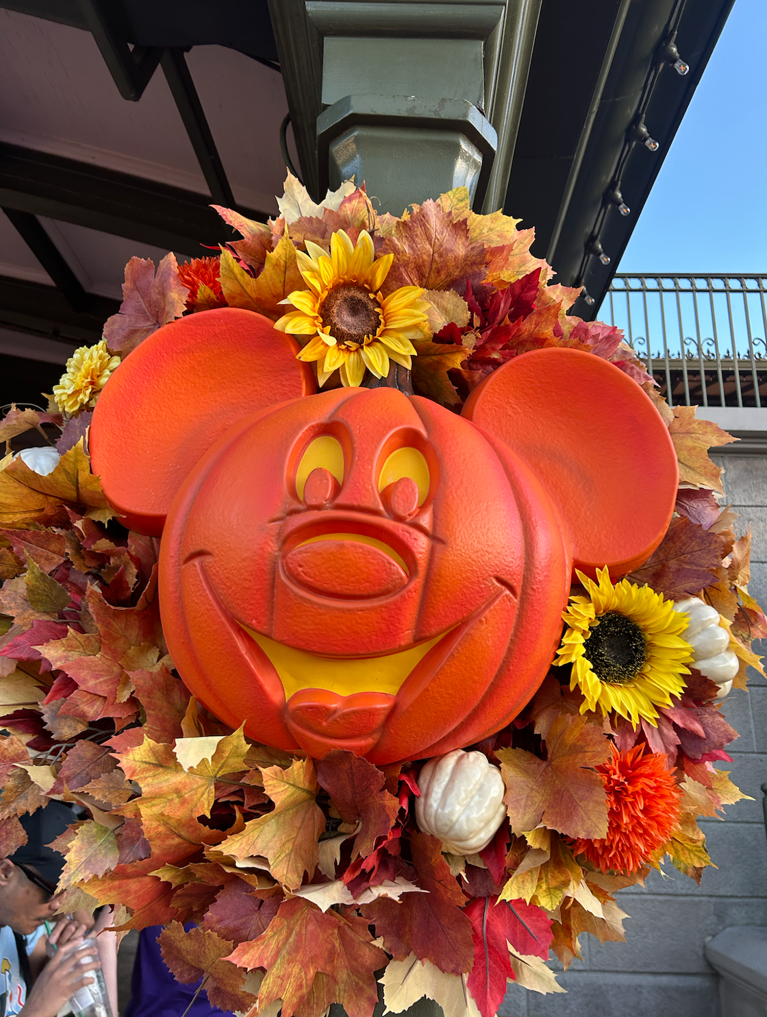 A Mickey Mouse head-shaped pumpkin is displayed in an autumnal wreath at Disney World.