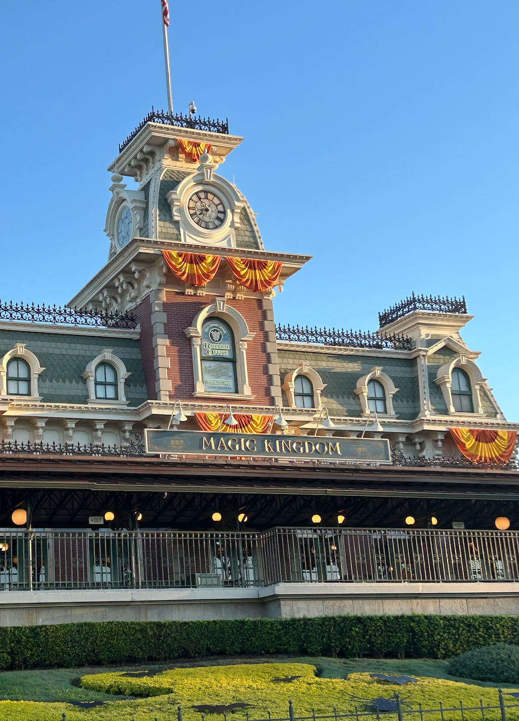 The entrance to Magic Kingdom at Disney World, decorated with orange and yellow colored flags for autumn.