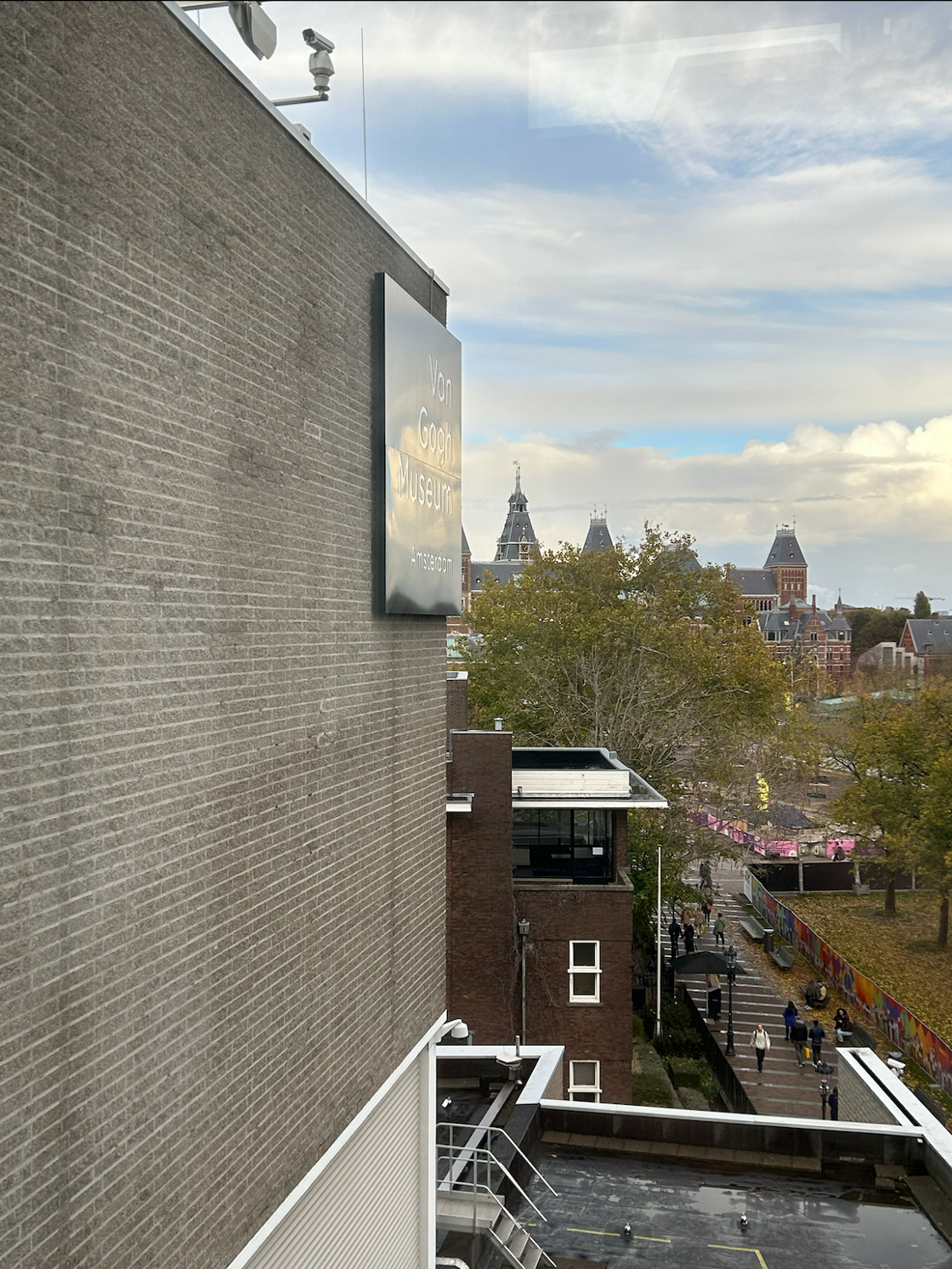 A view of the brick exterior of Van Gogh Museum from its picturesque balcony windows, looking out into Amsterdam at sunset.