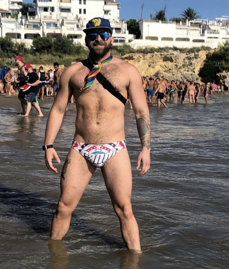 Man in Speedo with sunglasses and hat in the water