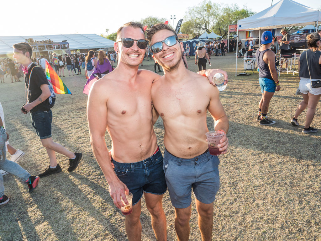 Two shirtless men with chiseled abs pose together during Phoenix pride.