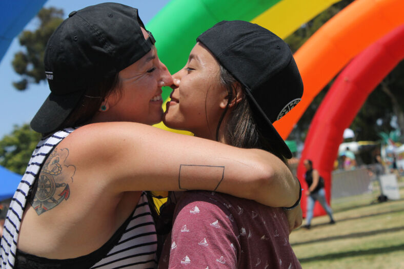 A couple kissing in front of an inflatable rainbow