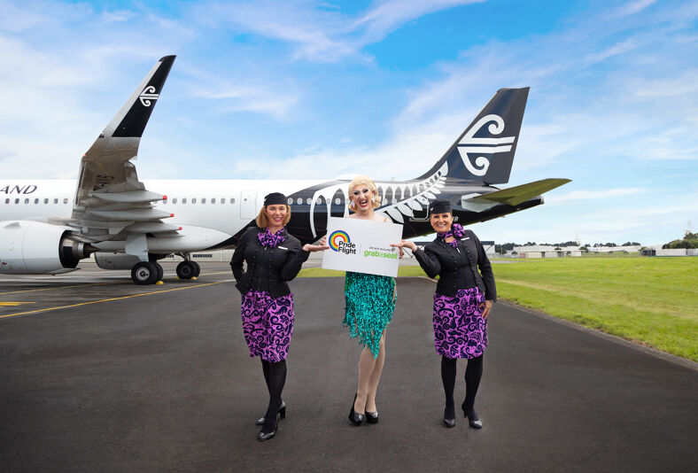 Air New Zealand flight attendants and drag queen on runway.